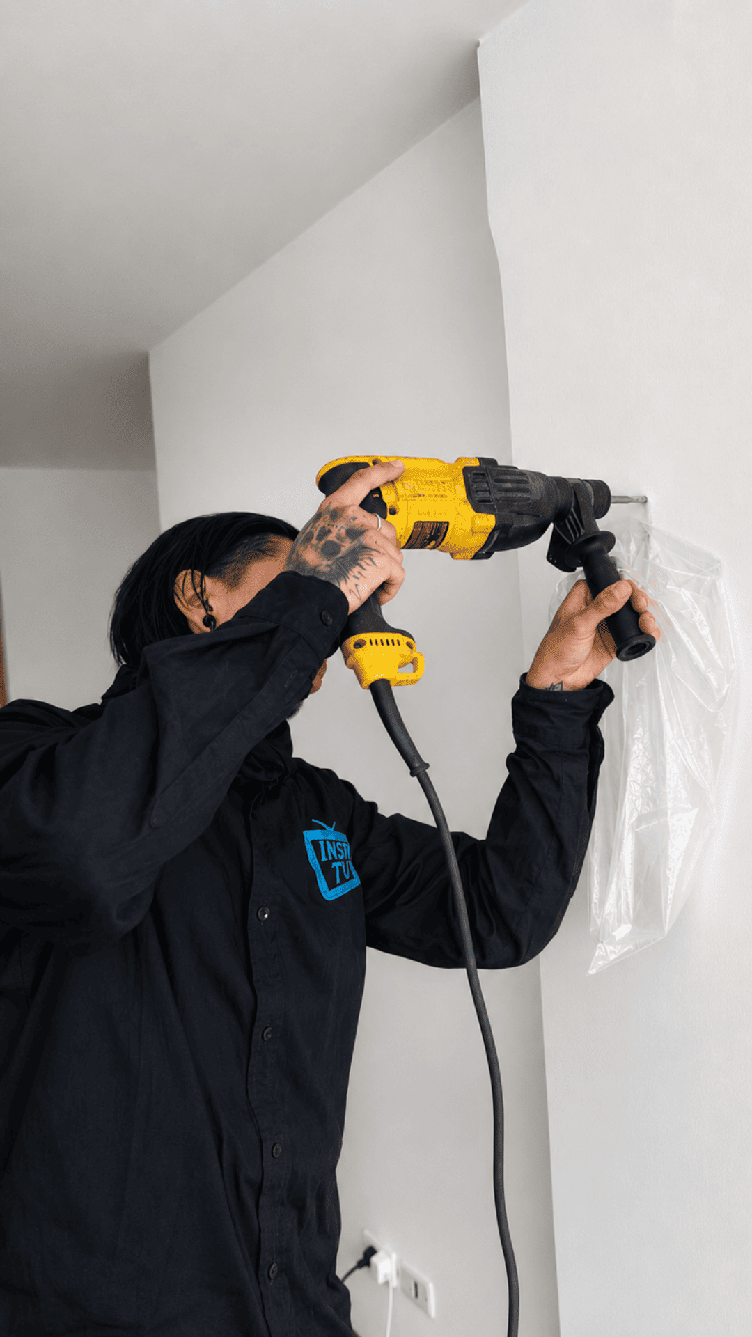 Técnico de InstaTV perforando muro con taladro para instalar soporte de TV